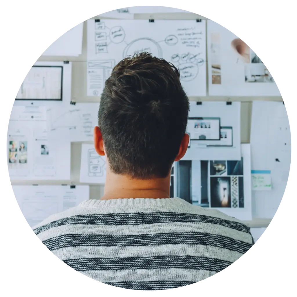 Person viewed from behind looking at whiteboard with diagrams and planning sketches