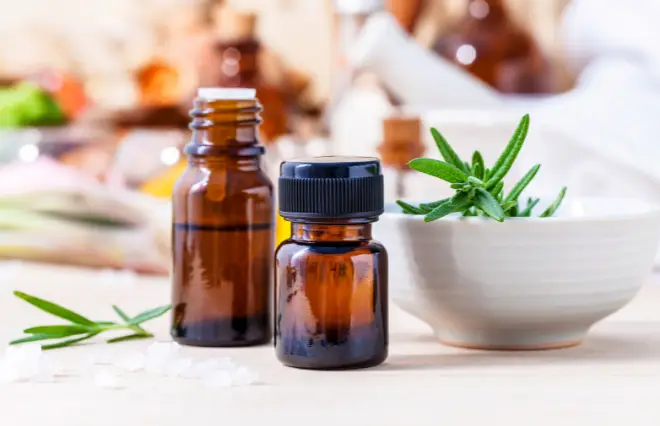 Rosemary essential oil bottles with fresh herb sprigs on white surface