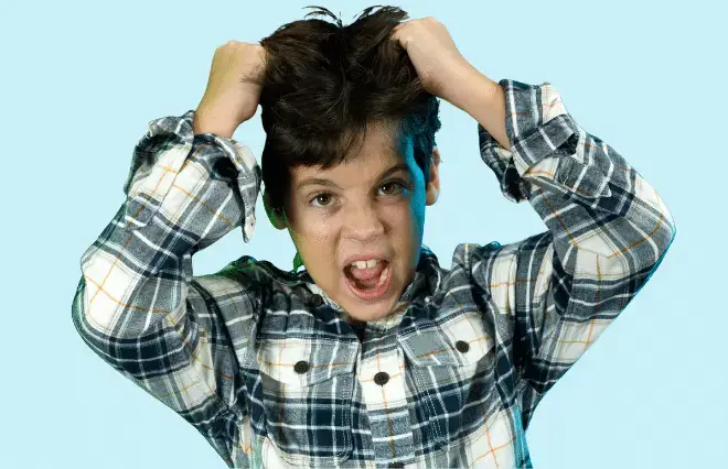 Child in plaid shirt with hands in hair making animated excited expression