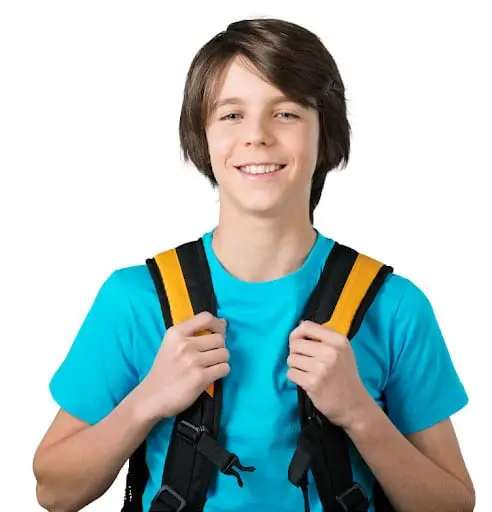 Smiling boy in blue shirt holding backpack straps