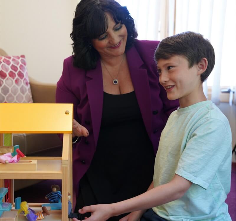 Dr. Roseann helping boy with educational toy