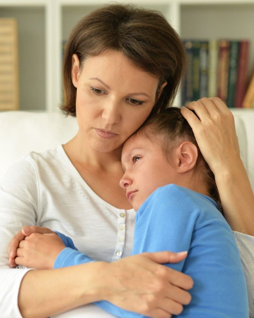 Mother comforting distressed child with empathetic embrace