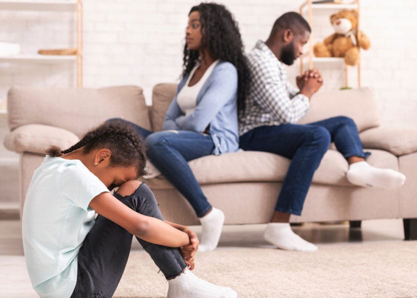 Family in living room, child sitting on floor while parents on couch