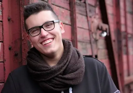 Teenager with glasses smiling at camera outdoors