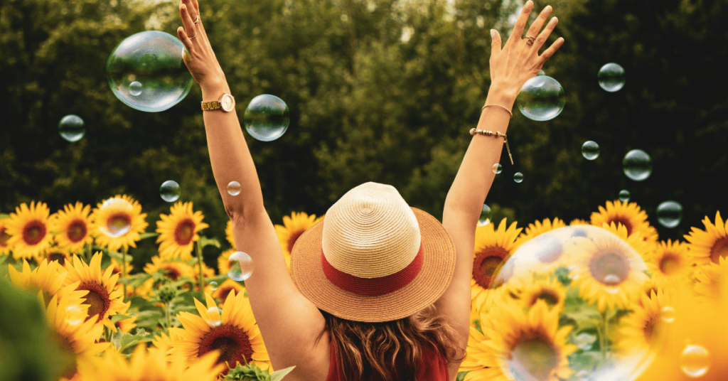 A woman joyfully surrounded by sunflowers in a field, promoting health and wellness.