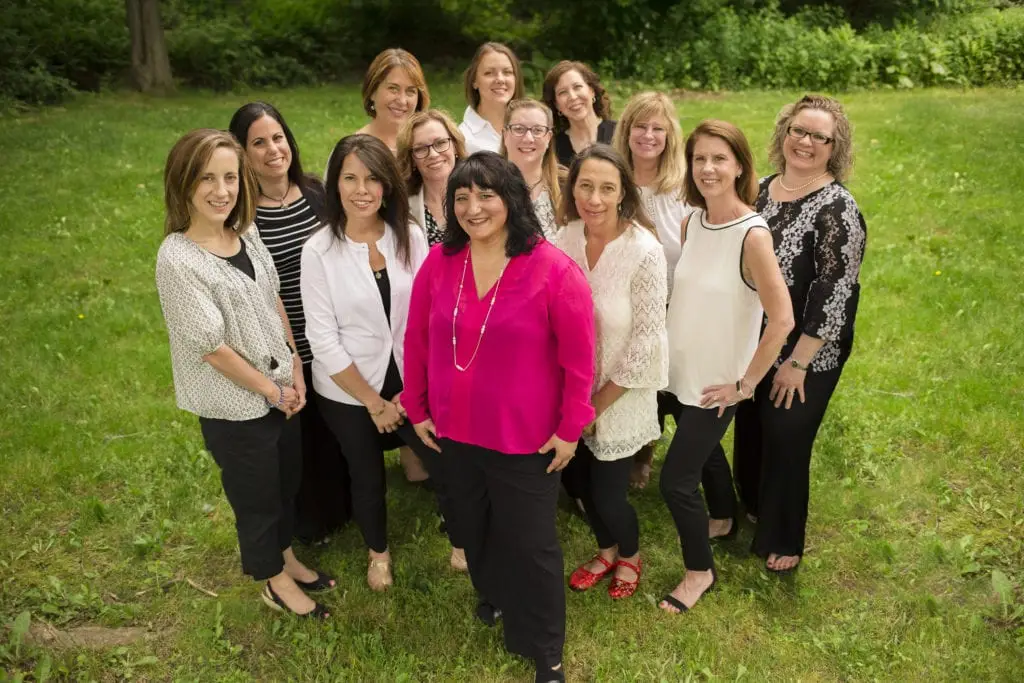 A group of women posing for a photo in a field.