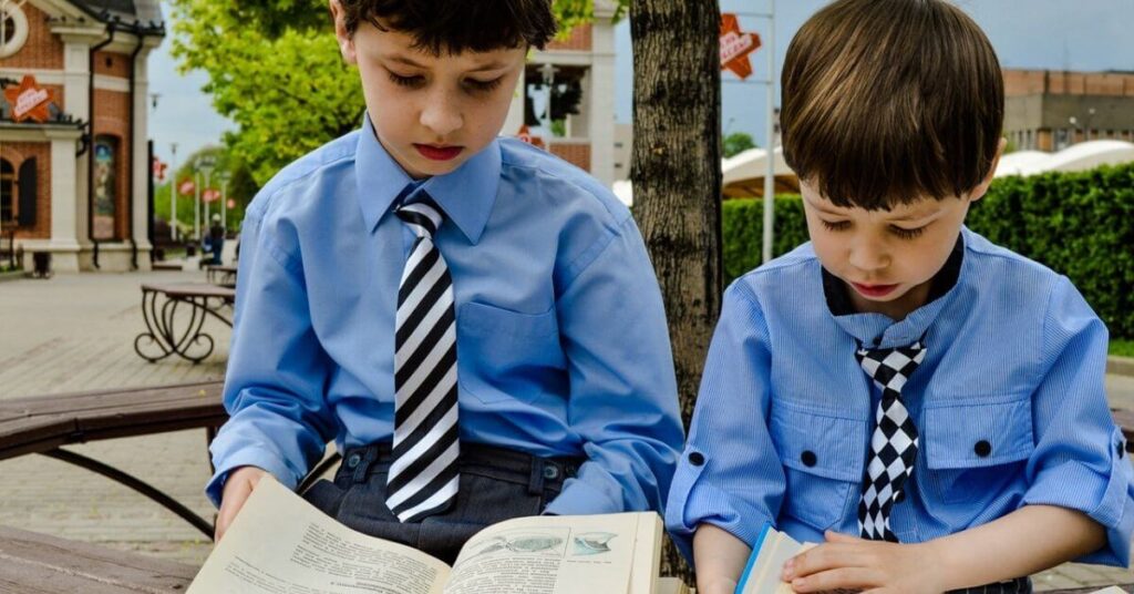 two young schoolboys reading outside