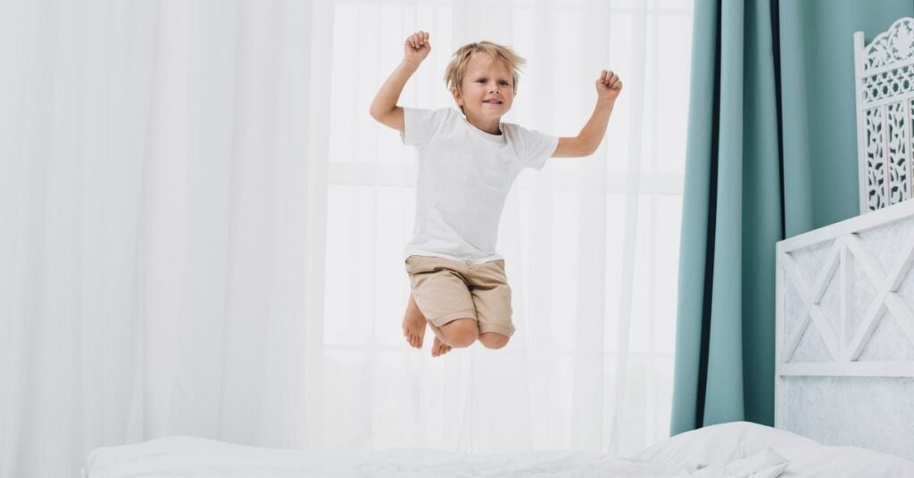 extroverted child jumping on bed