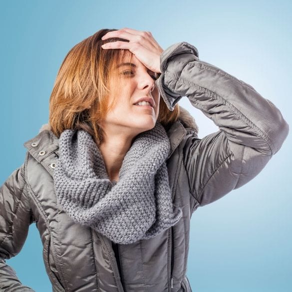 A woman with a cold is holding her head.