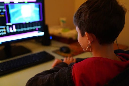 A young boy sitting in front of a computer screen.