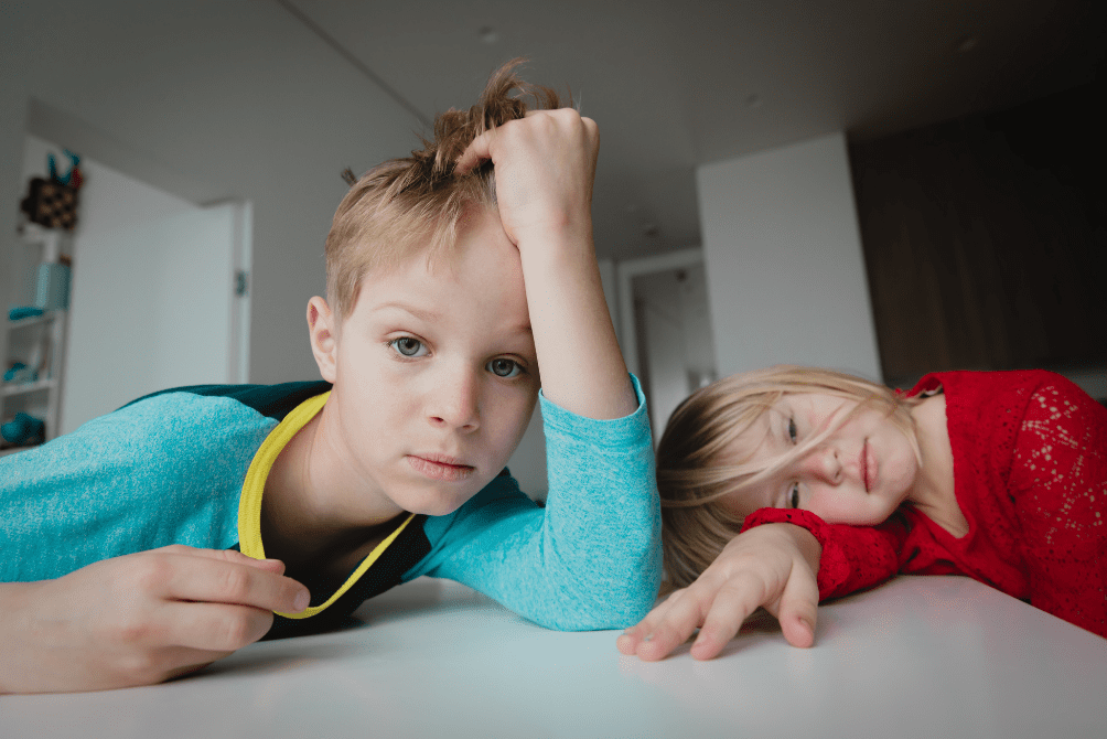 Two children displaying distress on a table, signifying the impact of the pandemic on their mental health.