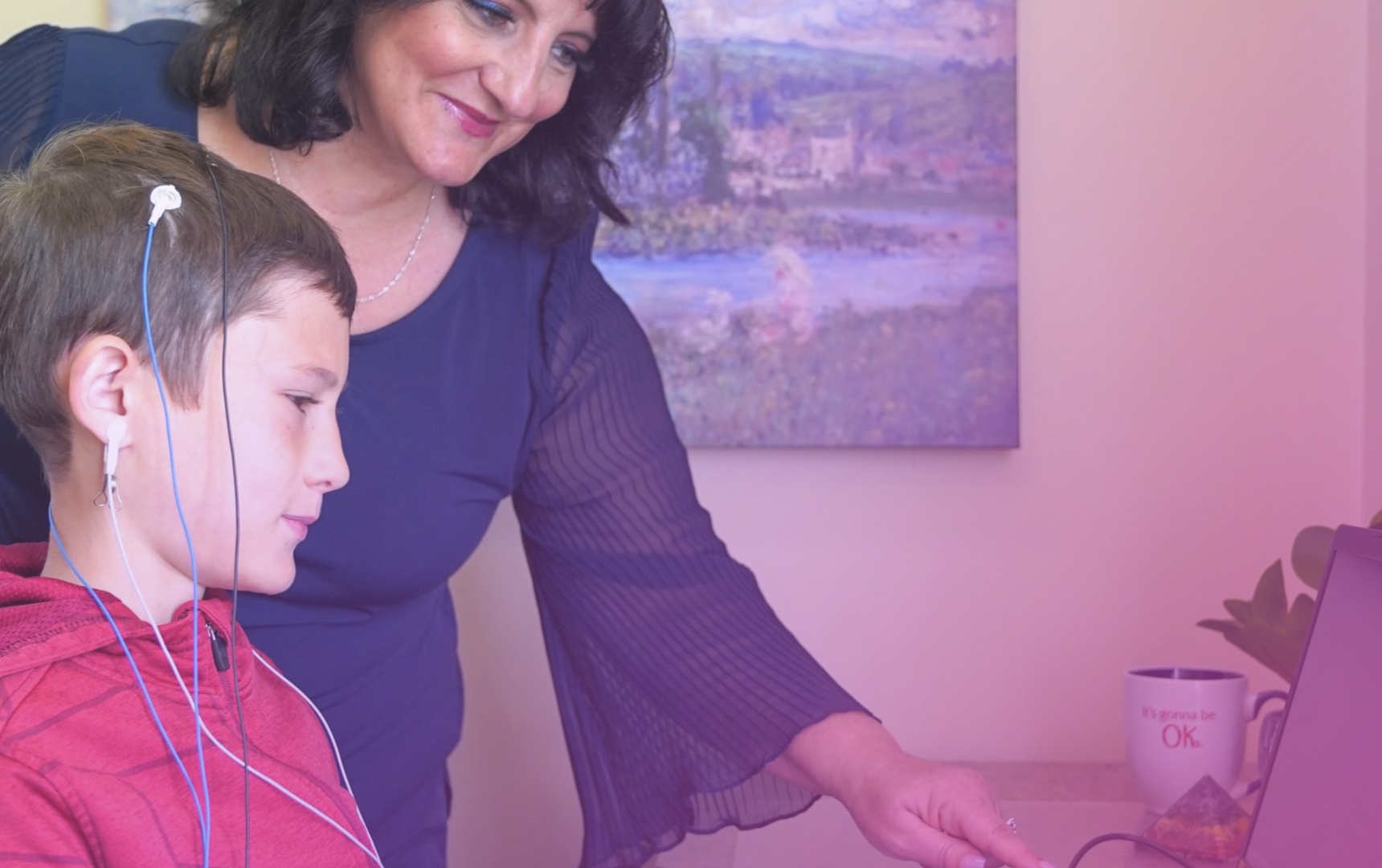 A woman is assisting a boy in computer programming using the BrainBehaviorReset™ Program.