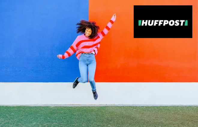 A woman posing in front of a colorful wall showcasing the word "huffpost" for media kit purposes.