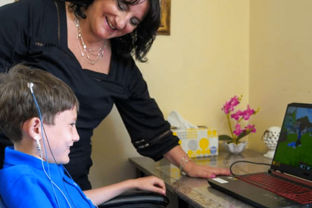 A woman in a wheelchair and a boy using a laptop to access a clinical guide for mood and behavior.