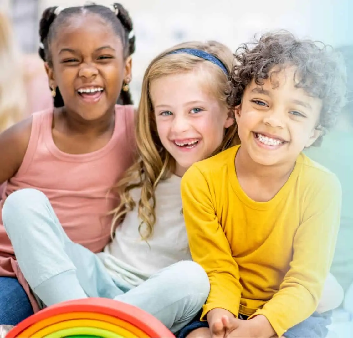 "Three smiling children standing together with a vibrant rainbow in the background, representing happiness, diversity, and positivity.