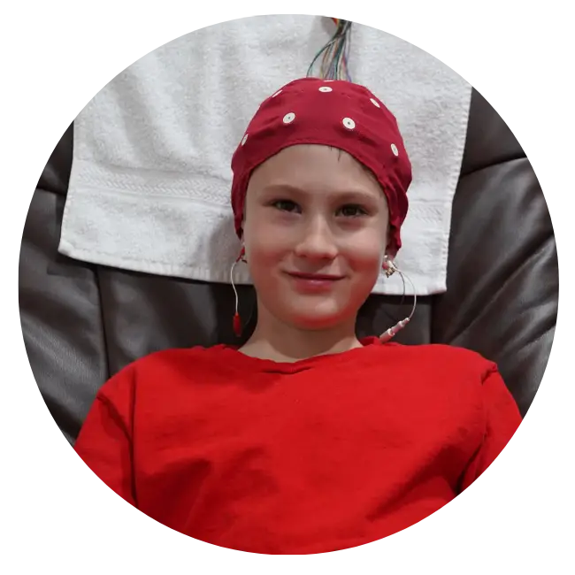 A young boy using neurofeedback technology, wearing a red polka dot hat.