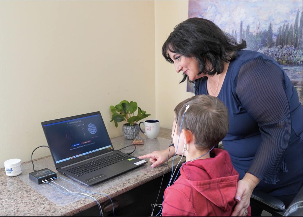 A woman is helping a young boy with his hearing aids.