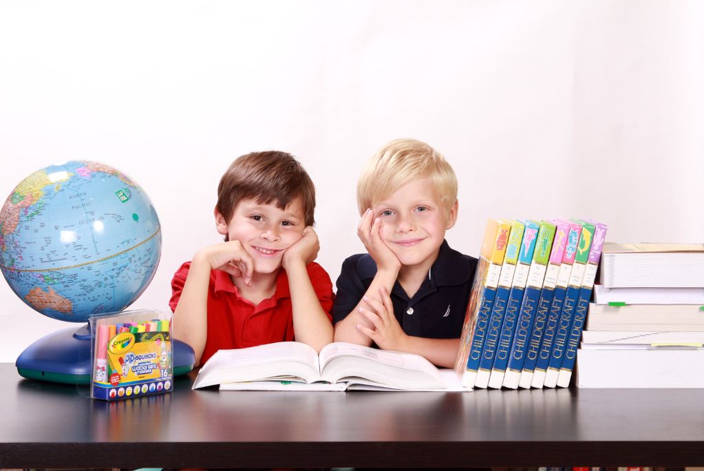 Two students achieving back to school success while sitting at a table with books and a globe.